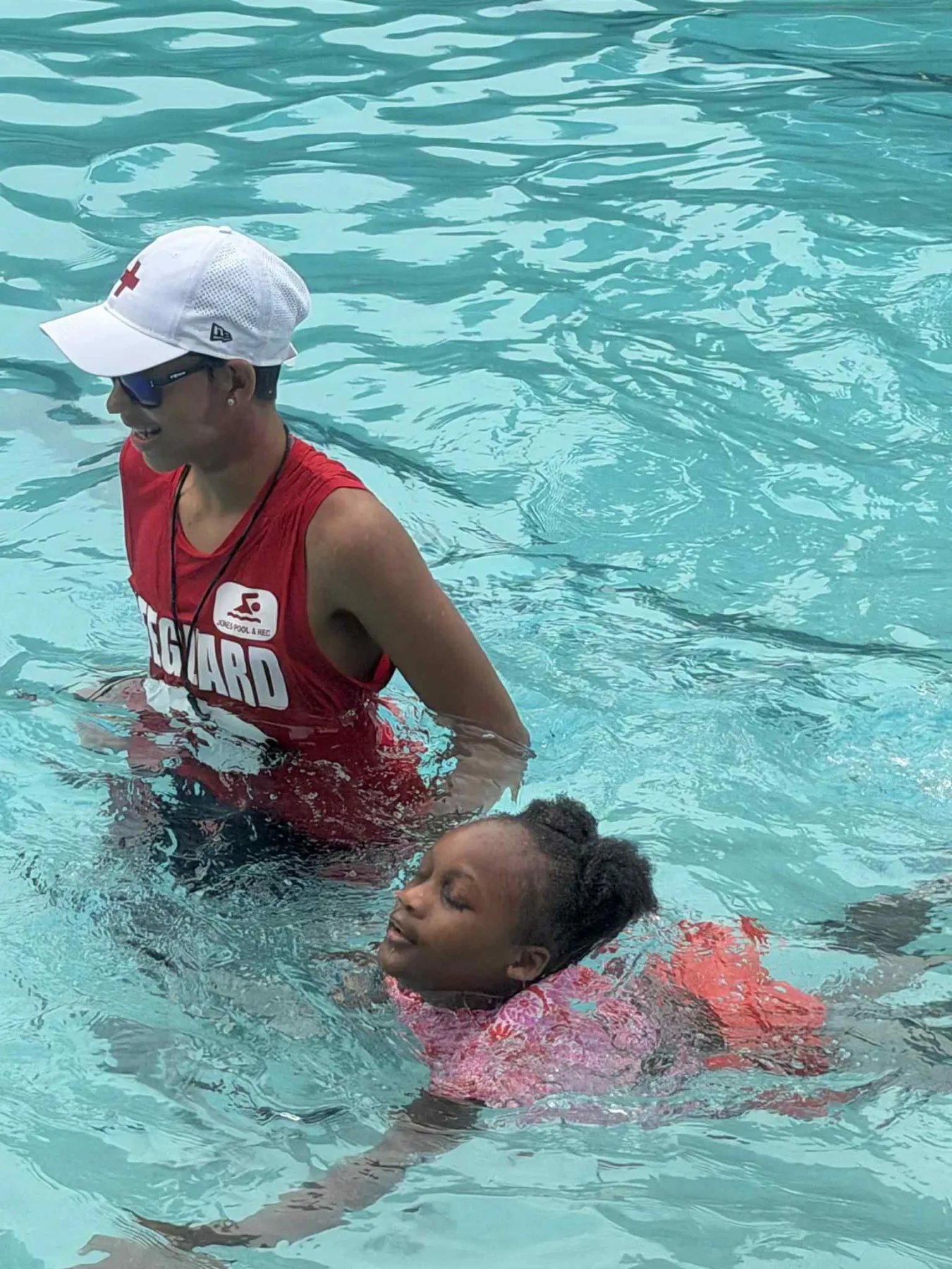 A lifeguard guiding a child during a swimming lesson