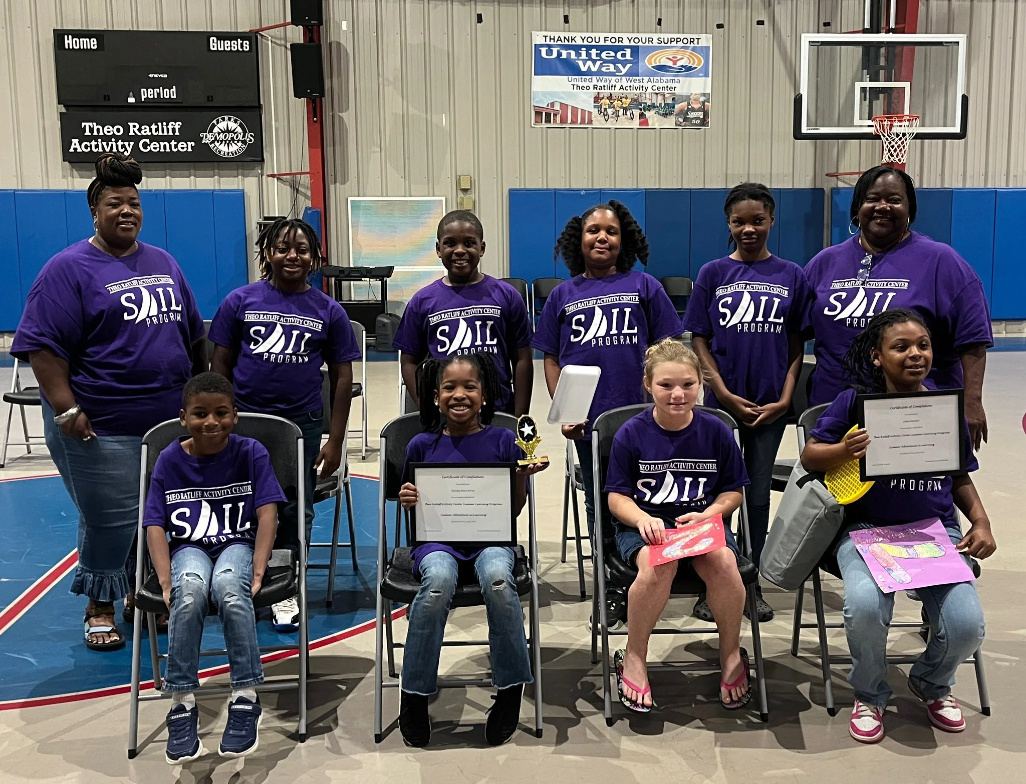 Children and program leaders celebrating the completion of a summer learning program at the center